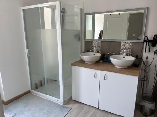 a bathroom with two sinks and a glass shower at Entre Lac et Mer in Clermont-lʼHérault