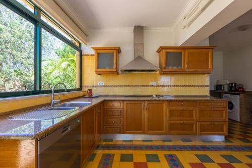 a kitchen with wooden cabinets and a sink and a window at Vila Limão in Boliqueime