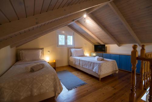 a attic bedroom with two beds and a tv at Petrochori Beach House in Voidokilia