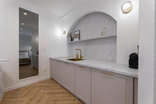 a white kitchen with a sink and a mirror at Palace Luxury Suites in Split