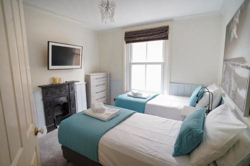 a bedroom with two beds and a fireplace and a television at Nutcroft, Cowes in Cowes