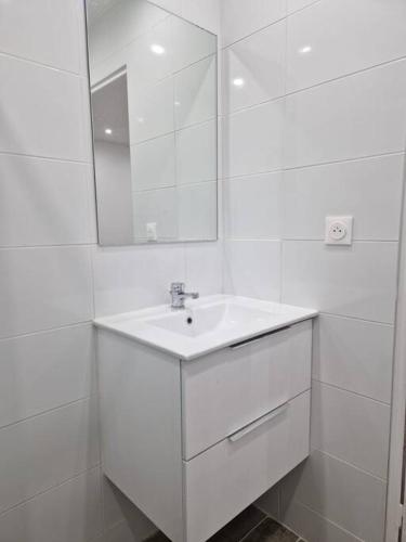 une salle de bain blanche avec un lavabo et un miroir dans l'établissement Joli studio calme contemporain CDG/PARC D'EXPO VILLEPINTE/PARIS, à Aulnay-sous-Bois