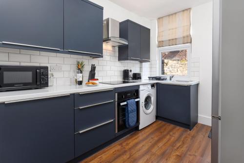 a kitchen with blue cabinets and a washer and dryer at Crawford Avenue Retreat in Liverpool