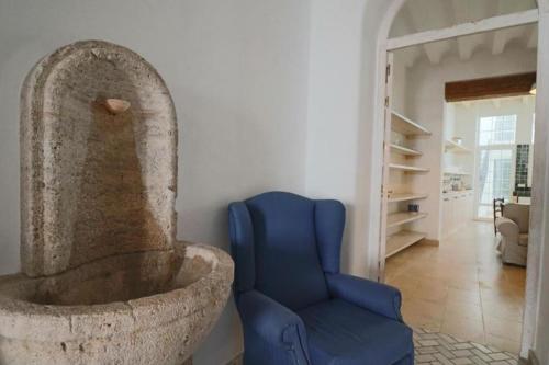a blue chair in a living room with a stone fountain at Apartamentos Castillo Quince in Cartaya