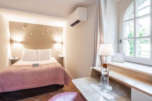 a bedroom with a bed and a table and a window at Le Domaine Du Colombier in Malataverne