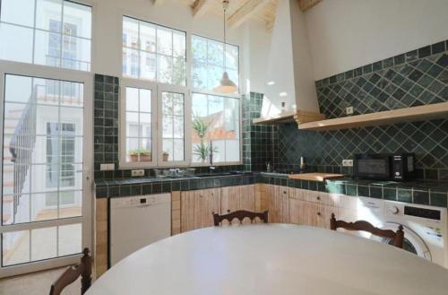 a kitchen with a large white table and some windows at Apartamentos Castillo Quince in Cartaya