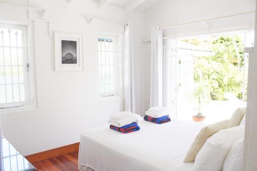 a white room with a bed with two pillows on it at Hummingbird in Saint James
