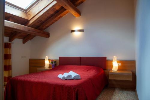 una camera da letto con un letto rosso con due asciugamani di Agriturismo Antico Splendore a Pullir