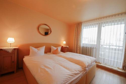 Schlafzimmer mit einem großen weißen Bett und einem Fenster in der Unterkunft Gästehaus Garni Merk in Immenstaad am Bodensee