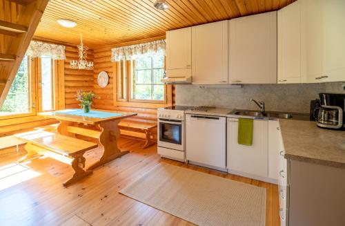 cocina con armarios blancos y suelo de madera en Villa Tuulahdus, Sorjosen lomamökit en Savonlinna