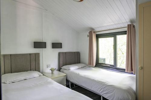 2 camas en una habitación con ventana en Barmouth Bay Holiday Park, en Barmouth