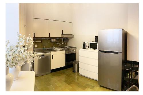 uma cozinha com armários brancos e um frigorífico de aço inoxidável em Elegant Apartment San Babila ,5 minutes from Duomo em Milão