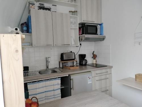 une petite cuisine avec un évier et un micro-ondes dans l'établissement Entre MER et MONTAGNE, à Granville
