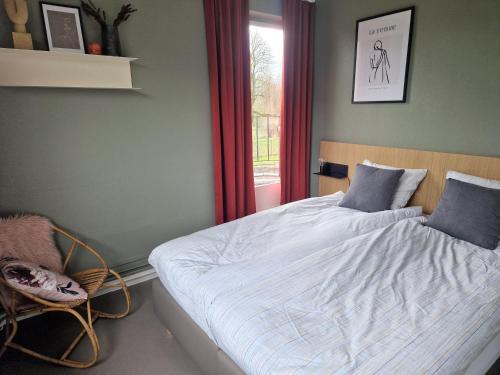 a bedroom with a bed with a window and a chair at Villa Op de Voort (XL, 12-22 personen) in Heusden - Zolder