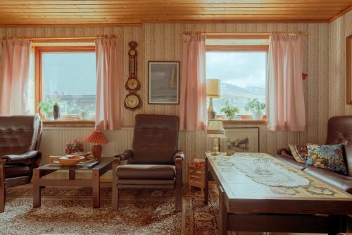 a living room with a couch and a table and two windows at 3-Bedroom Home in Eiði 