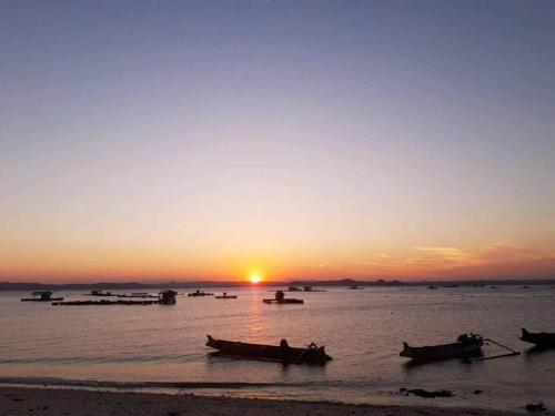 a group of boats in the water at sunset at Satu Hati Homestay in Ekas