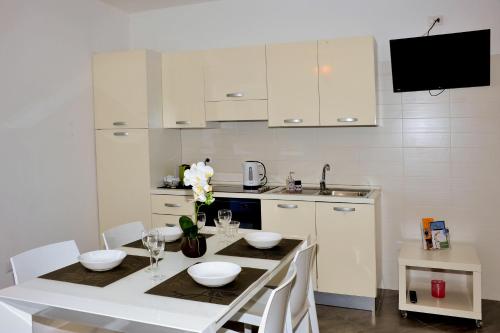 une cuisine avec des placards blancs et une table avec des bols dans l'établissement MARIMAR - Apartments OTRANTO, à Otrante