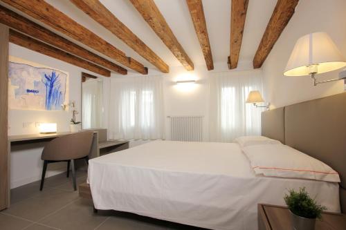 Schlafzimmer mit einem weißen Bett und einem Schreibtisch in der Unterkunft Residence degli Artisti in Venedig