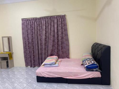 a bed in a room with a purple curtain at iena homestay in Kampong Bongaliu