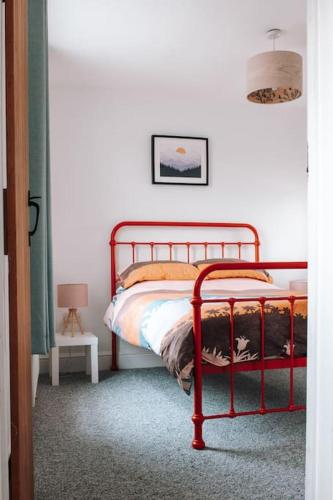 a bedroom with a red metal bed in a room at Albion Cottage central Falmouth with parking and 10 minutes to the beach in Falmouth