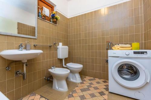 ein Badezimmer mit einem WC, einem Waschbecken und einer Waschmaschine in der Unterkunft Delux Sandy Beach (Duće) in Duće