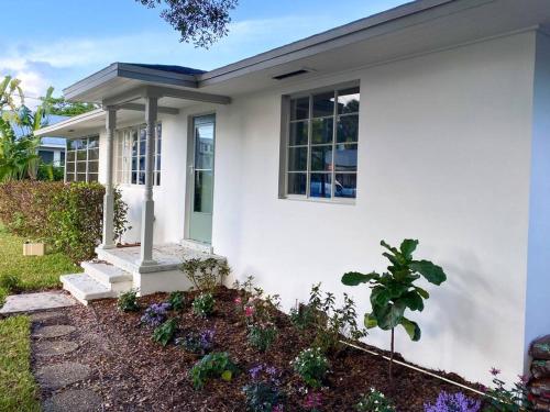a white house with flowers in front of it at Cozy Renovated Vintage Modern House Downtown! in Fort Myers