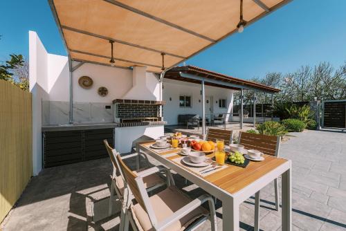 een tafel en stoelen op een patio met een keuken bij Reni Garden House in Afantou