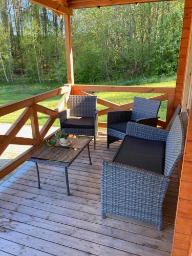 a porch with chairs and a table on a wooden deck at Zarasaičio ežero sodyba in Magučiai
