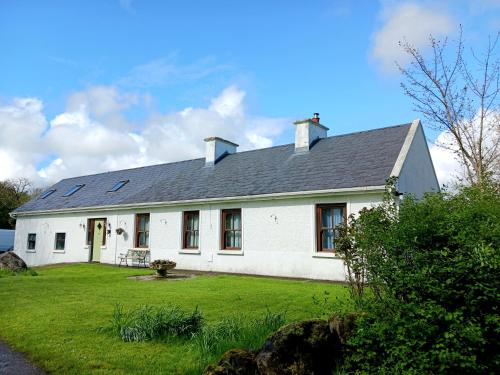uma casa branca com um grande quintal com um relvado verde em Rural retreat near Knock em Ballyhaunis