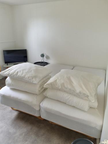 a stack of white pillows on a bed in a room at Feriehuse Hvide Sande in Hvide Sande