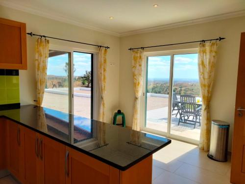a kitchen with a counter and a large window at Prestige for Home - Moradia Vista Mar, Piscina, Jardim e Estacionamento in Nora