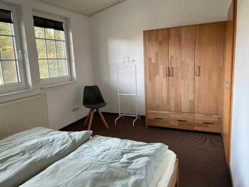 a bedroom with a bed and a cabinet and a chair at Landhaus am Loh in Wesel