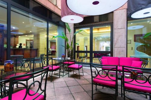 a restaurant with pink chairs and tables and windows at Hotel dei Mellini in Rome