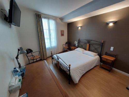 een slaapkamer met een bed en een flatscreen-tv bij Logis - Le relais des deux vallées in Salvagnac