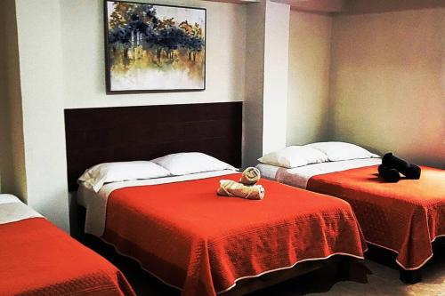 a bedroom with two beds with red sheets and a teddy bear sitting on at Loft Centrico 4 camas ,Aire acondicionado,WIFI, parking, refrigerador, microhondas in Ciudad Valles