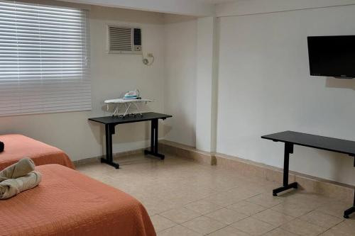 a room with two beds and a desk and a television at Loft Centrico 4 camas ,Aire acondicionado,WIFI, parking, refrigerador, microhondas in Ciudad Valles