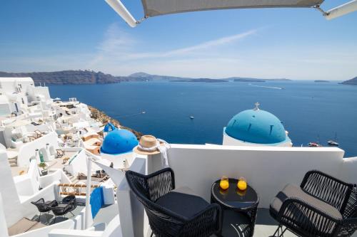 a balcony with chairs and a view of the ocean at Luxus VIP Suites in Oia