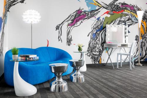 a living room with a blue couch and a mural at Studio Allston Hotel Boston in Boston