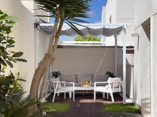 patio ze stołem, krzesłami i palmą w obiekcie Villa Mil Palmeras w mieście Campoamor