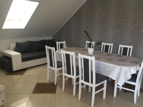 a dining room with a table and chairs and a couch at POKOJE GOŚCINNE RENATA KNITTER in Komnino