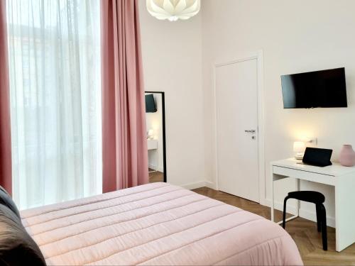 a bedroom with a bed and a desk and a television at Glamour Suite Cagliari in Cagliari
