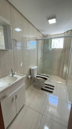 a bathroom with a toilet and a sink at Apto Lírio da Paz- 3 Quartos com sacadas,espaçoso e de frente para avenida principal! in Piratuba