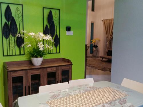 a dining room with a table and a green wall at MY KIJANG HOMESTAY - Banglo, Alor Setar Kedah DarulAman in Alor Setar