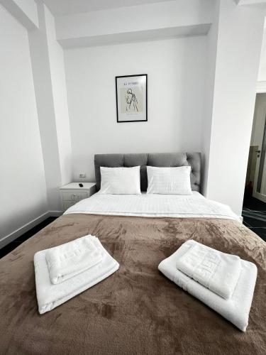 a bedroom with a large bed with two white towels on it at Marvellous Aparthotel with Master Apartments Suceava in Suceava