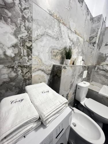 a bathroom with a sink and a toilet and towels at Marvellous Aparthotel with Master Apartments Suceava in Suceava