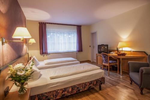 a hotel room with two beds and a desk at Waldsee Hotel am Wirchensee in Treppeln