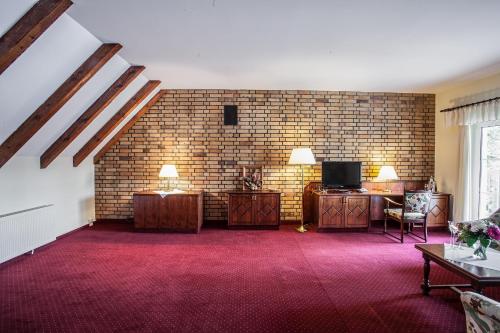 a living room with a brick wall and a tv at Waldsee Hotel am Wirchensee in Treppeln