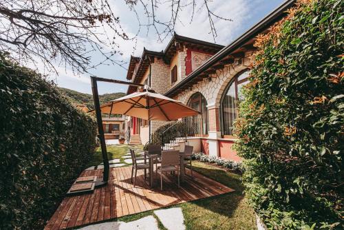 una terraza de madera con mesa y sombrilla en Villa Riva, en Badia Calavena