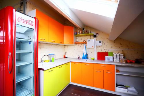 une cuisine avec des armoires orange et jaune et un réfrigérateur cocacola. dans l'établissement ID Hostel Rostov-on-Don, à Rostov-sur-le-Don