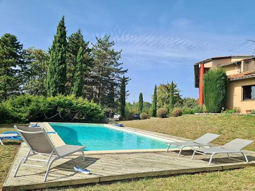 einen Pool mit zwei Stühlen und ein Haus in der Unterkunft Chambres d hotes, la maison de Kat in Lamothe-Capdeville
